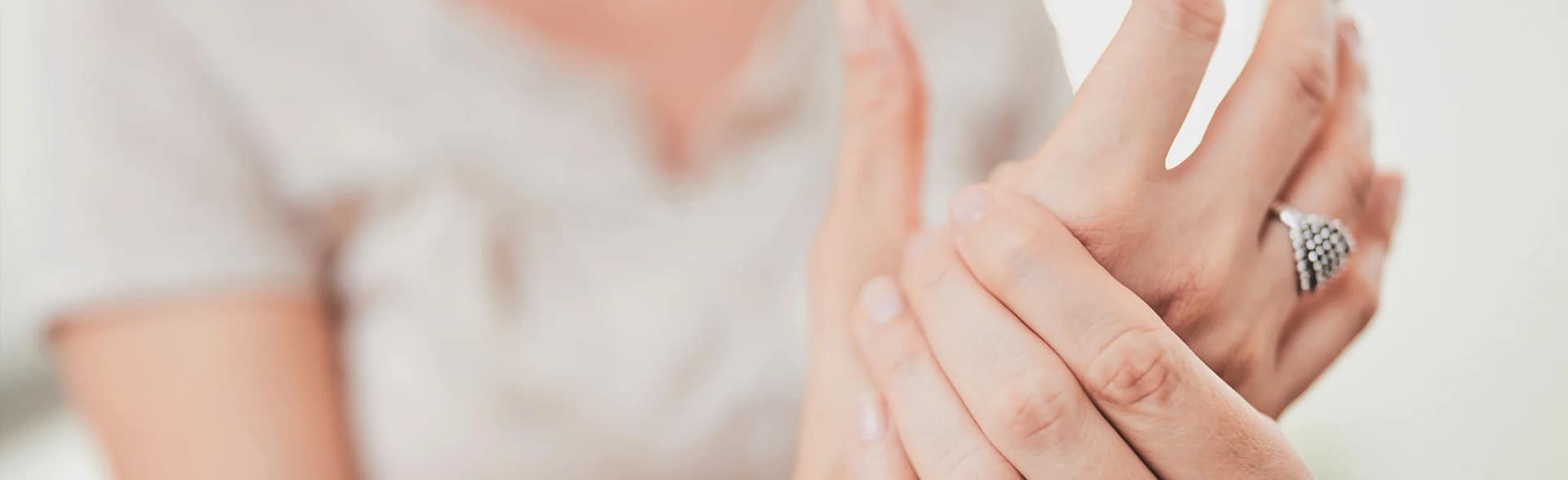 Woman holding hand due to thumb pain, suffering with Skiers Thumb and ligament damage.